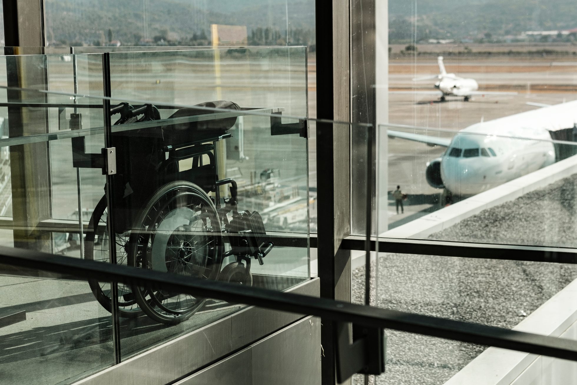 Wheelchair at the airport by the window. View out the window of the runway, planes ready for take-off.